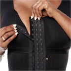 Black waist trainer with metal hooks worn by a person, close-up view.
