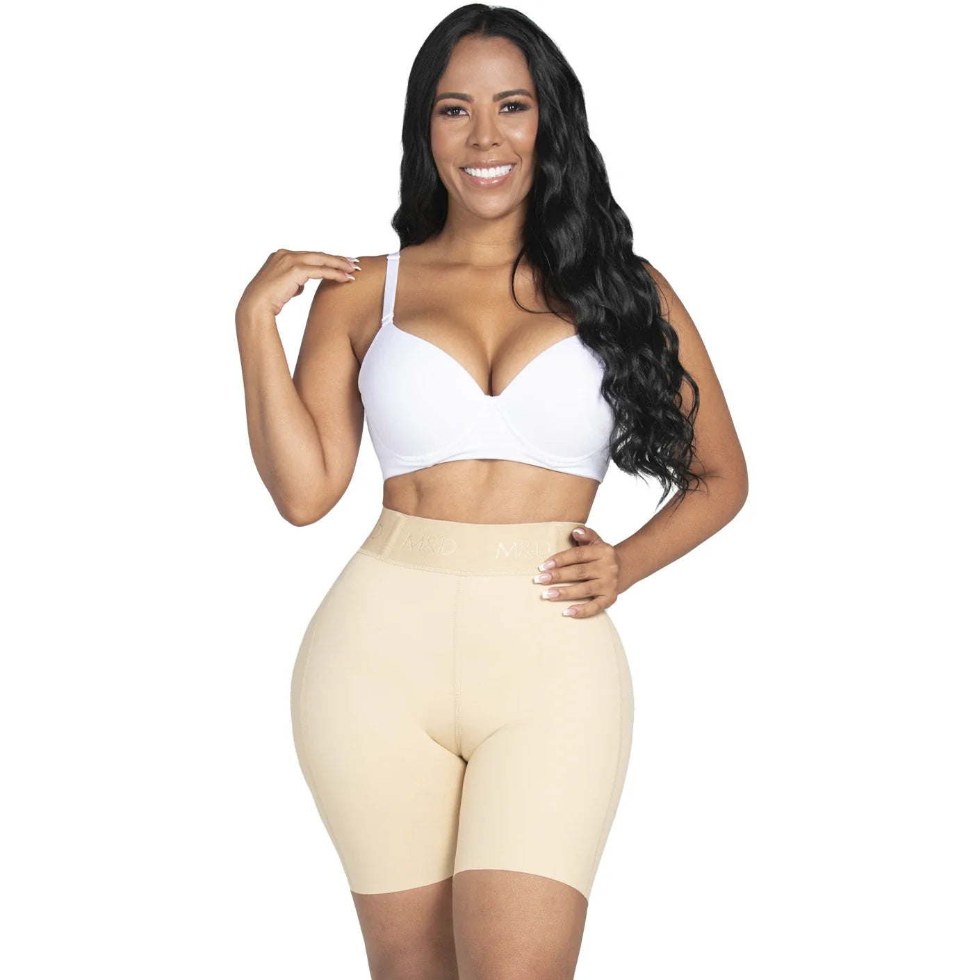 Woman wearing a white sports bra and beige shapewear on a white background