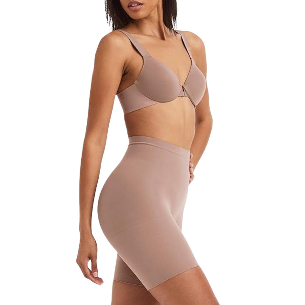 Woman wearing a beige bra and shapewear on a white background