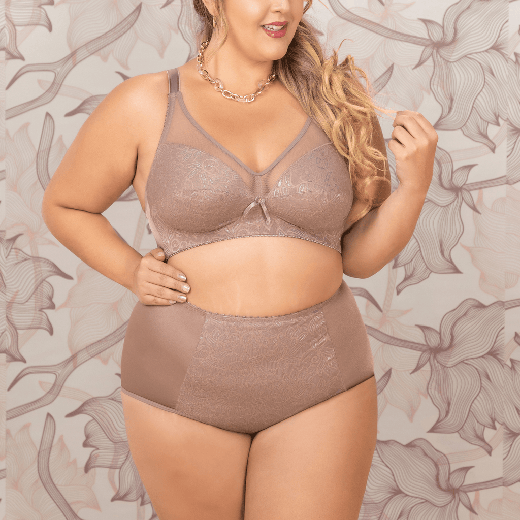 Woman wearing a brown lingerie set against a floral patterned wall.