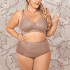 Woman wearing a brown lingerie set against a floral patterned wall.