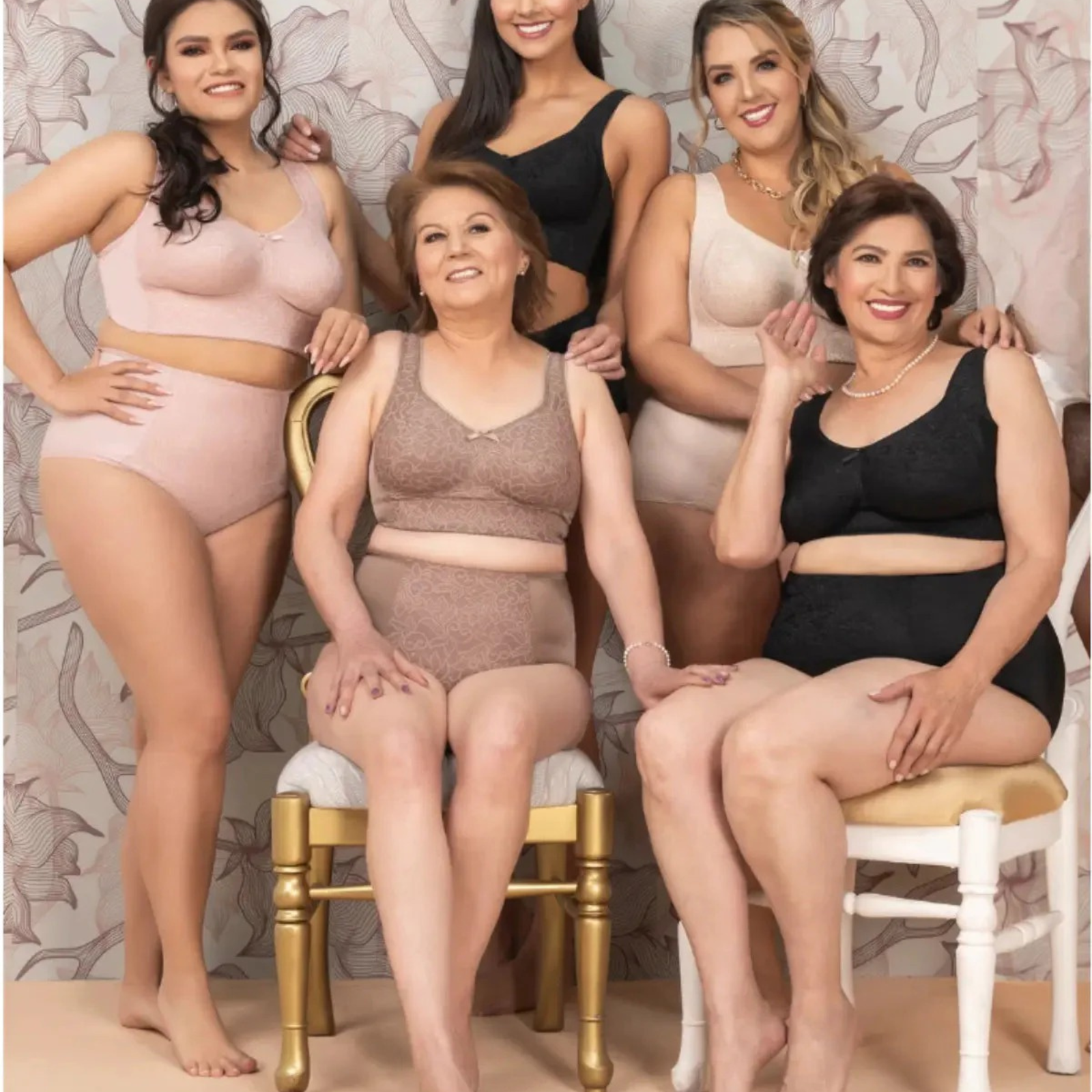Group of women wearing lingerie posing together against a floral wallpaper background.