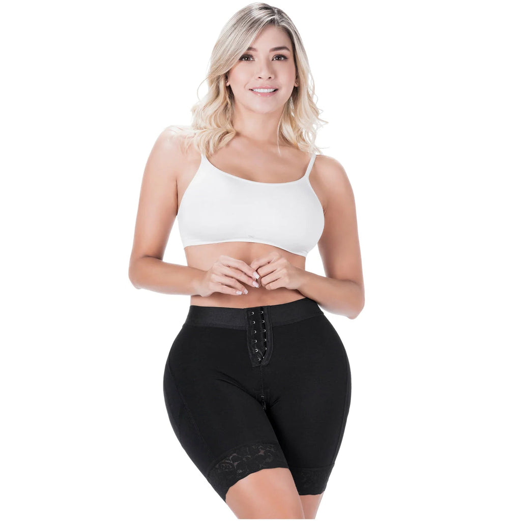 Woman wearing a white sports bra and black compression shorts on a white background