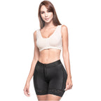 Woman wearing a beige crop top and black shapewear on a white background