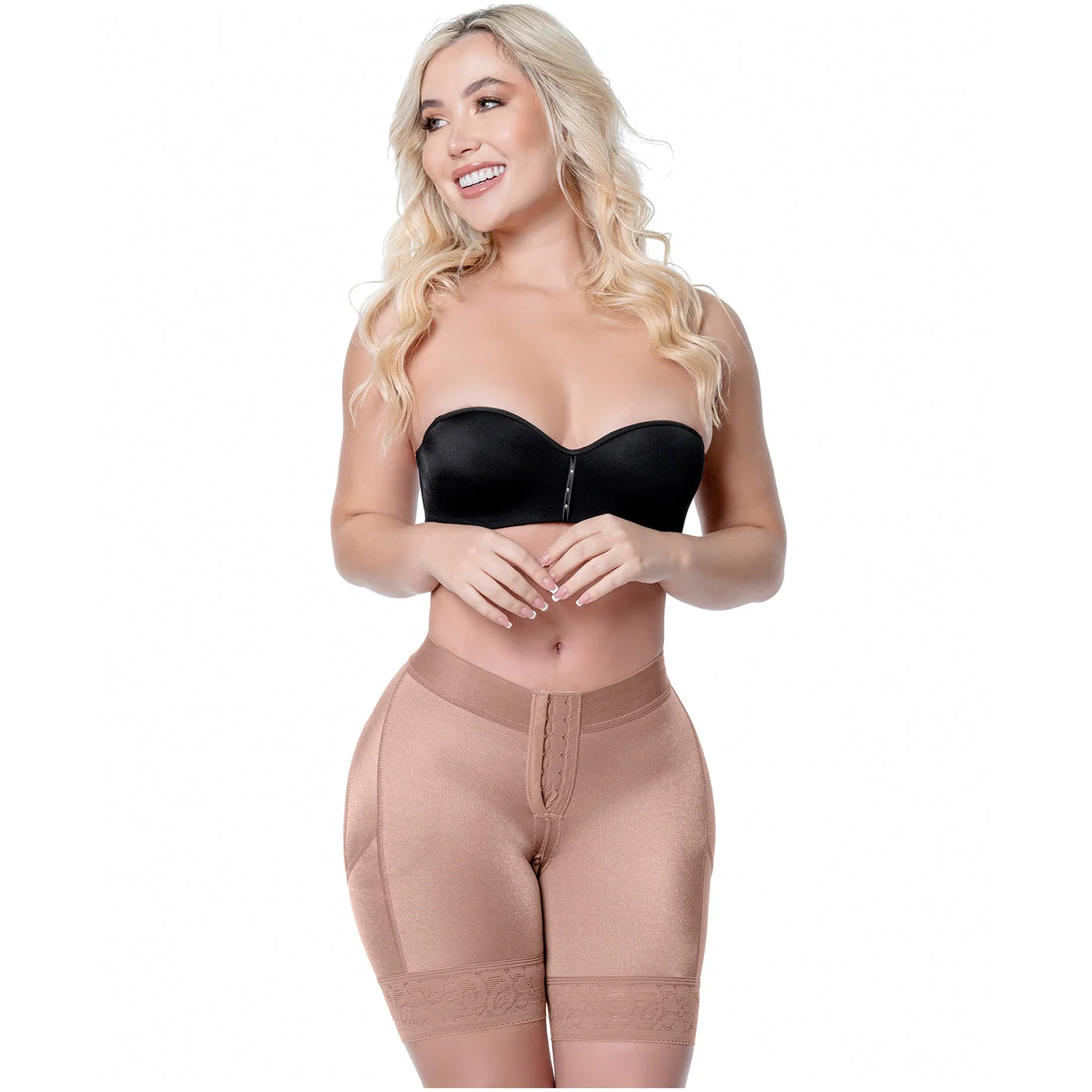Woman wearing a black strapless top and beige shapewear on a white background
