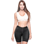Woman wearing a white sports bra and black shapewear shorts on a white background