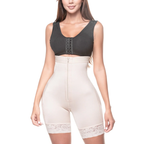 Woman wearing a black crop top and beige shapewear on a white background