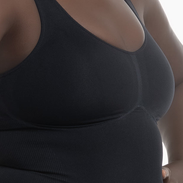 Close-up of a person wearing a black tank top against a neutral background