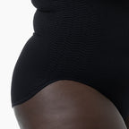 Black bodysuit worn by a person on a white background