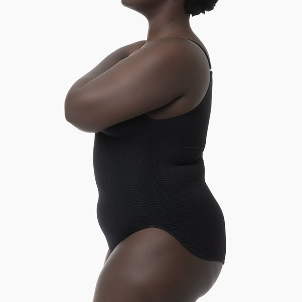 Person wearing a black bodysuit against a white background
