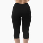 Black capri leggings worn by a person on a white background