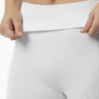 Close-up of a person wearing white textured pants with hands adjusting the waistband.