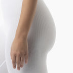 Close-up of a person wearing a textured white garment with a hand visible.