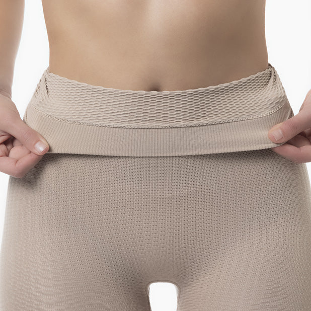 Beige compression garment being held up to show fit on a person.