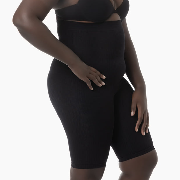 Person wearing a black shapewear garment on a white background