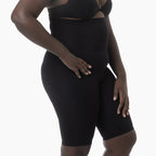 Person wearing a black shapewear garment on a white background