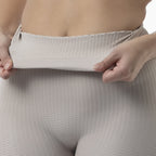 Person wearing beige mesh underwear with a plain background