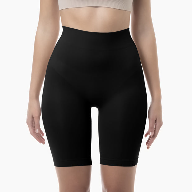 Black high-waisted shapewear shorts worn by a person on a white background