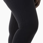Close-up of black leggings with a textured pattern on a white background