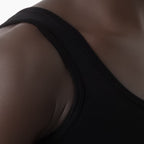 Close-up of a person wearing a black tank top on a white background