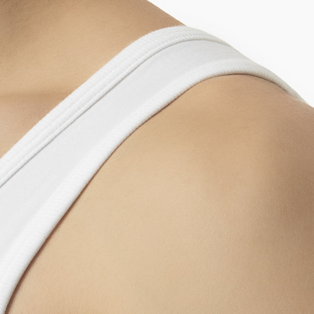 Close-up of a person wearing a white bra on a beige background