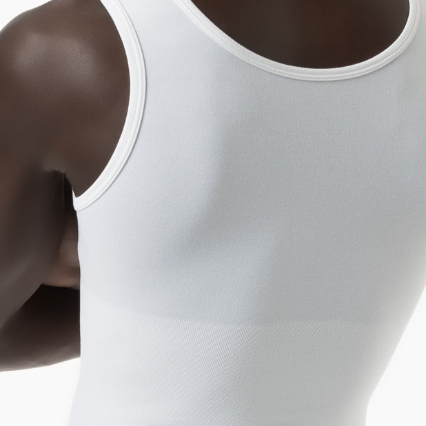 Close-up of a person wearing a white tank top on a neutral background