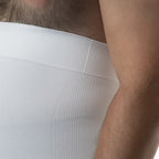Close-up of a person wearing a white ribbed shirt with a neutral background