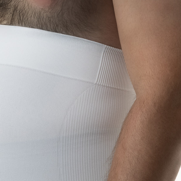 Close-up of a person wearing a white ribbed shirt with a neutral background