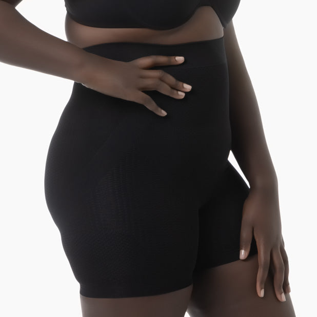 Person wearing a black shapewear garment on a white background