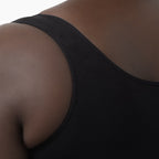 Close-up of a person wearing a black tank top on a white background